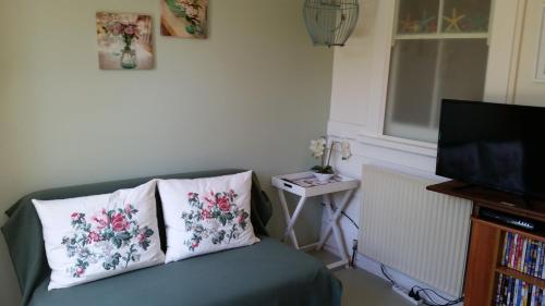 a living room with a couch with two pillows and a television at Delightful Cottage in Queenscliff