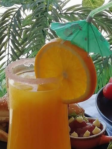 a glass of orange juice with an orange slice at SHALLY RESIDENCE 1 in Al Khobar