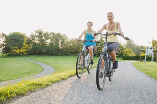two men riding bikes down a road at Thermenhotel PuchasPLUS Stegersbach in Stegersbach