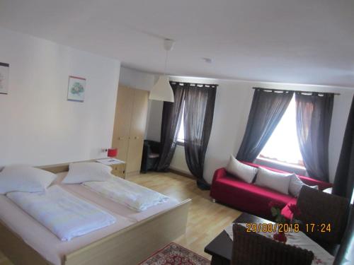 a bedroom with a bed and a couch and windows at Pension-Puttlachtal in Pottenstein