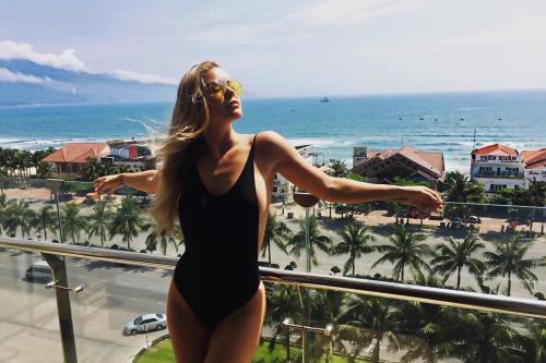 a woman standing on a balcony looking out at the beach at Diamond Sea Hotel in Da Nang