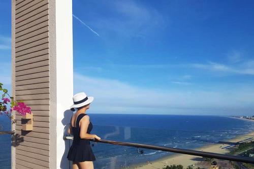 a woman standing on a balcony looking at the ocean at Diamond Sea Hotel in Da Nang