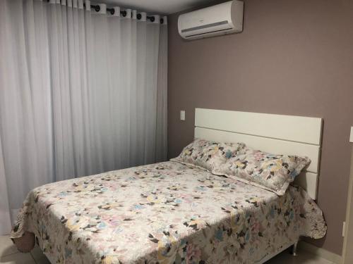 1 dormitorio con 1 cama con edredón de flores en Apartamento Aconchegante Em Arraial Do Cabo, en Arraial do Cabo