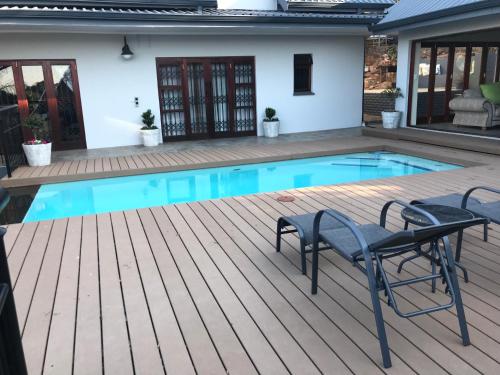 a swimming pool with a deck and chairs next to a house at Bokamoso Views in Rustenburg