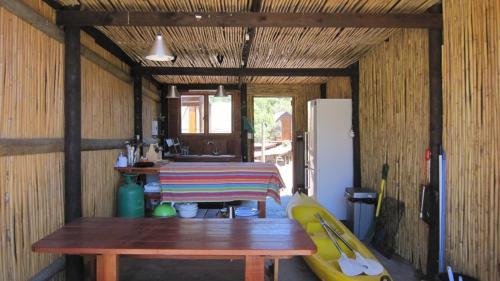 a room with a wooden table and a refrigerator at Koensrust Tented River Camp in Vermaaklikheid