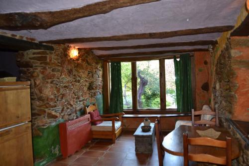 sala de estar con pared de piedra y ventana en Louteiro de las Médulas, en Orellán