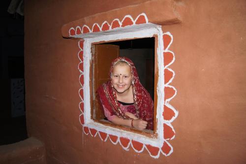 a girl looking out of a window in a house at Chhotaram Prajapat Home Stay in Jodhpur