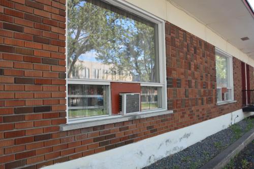 a brick wall with windows and a air conditioner at Motel Chez Nous in Laval