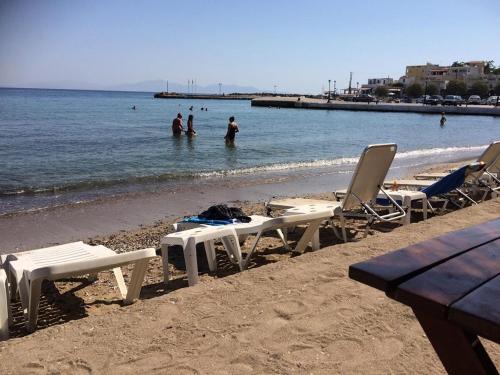 a beach with chairs and people in the water at Villa VS in Vathí