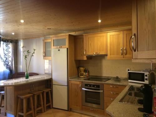 a kitchen with wooden cabinets and a white refrigerator at Alojamento Pelourinho in Melo