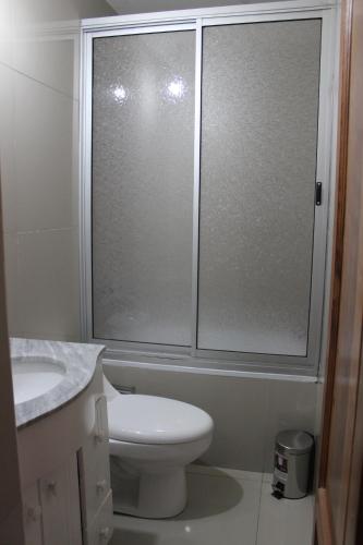 uma casa de banho com um WC e uma porta de duche em vidro. em MeStizO HostaL em Santiago