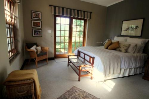 a bedroom with a bed and a chair and windows at The Bergzicht Guest Suite in Cape Town