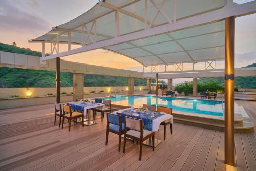 a pool with tables and chairs next to a swimming pool at SKK Blu Hotel & Spa in Udaipur