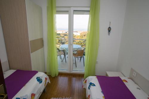 a room with two beds and a table and a window at Agata Apartments in Novalja