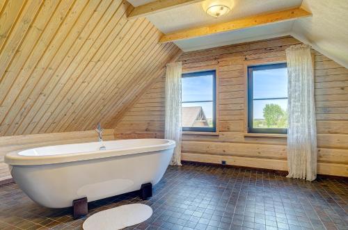 bañera blanca en una habitación con paredes de madera en Country house Stirnamis en Mindūnai