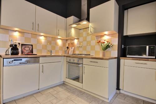 a kitchen with white cabinets and white appliances at Thier à Liege - hauts-sart in Liège