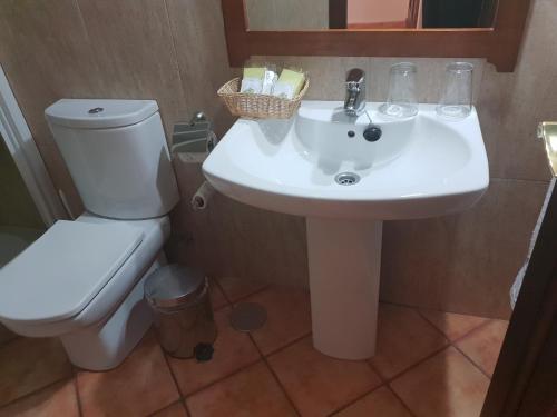 a bathroom with a white sink and a toilet at Hospedería Ana Pilar in Porcuna