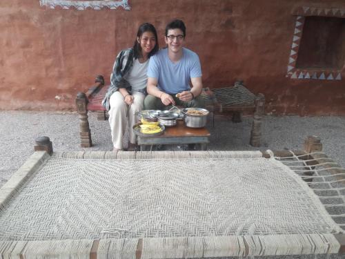 a man and woman sitting next to a table with food at Chhotaram Prajapat Home Stay in Jodhpur