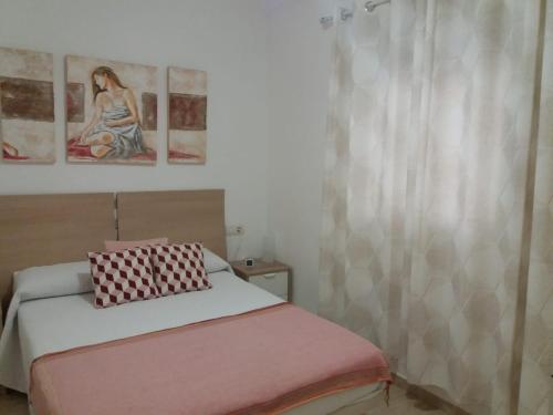 馬拉加的住宿－Apartamento Dos Aceras，卧室配有一张床,墙上挂有两幅画