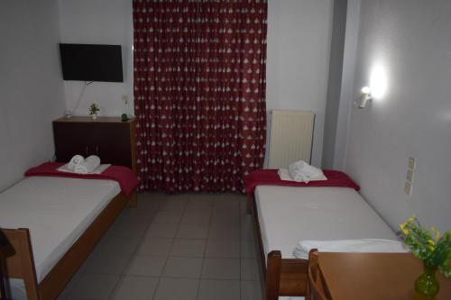 two beds in a room with a red curtain at Galanis Studios and Apartments in Platamonas