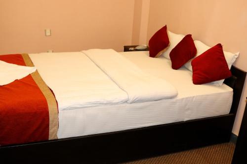 a bed with red pillows on it in a room at Hotel Nepalaya in Kathmandu