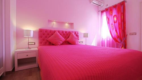 a pink bedroom with a pink bed and a window at Efharis in Kamares