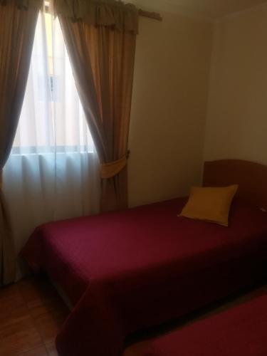 a bedroom with a red bed and a window at Casa Huespedes Angoba in Arica
