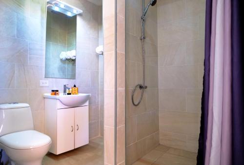 ein Bad mit einer Dusche, einem WC und einem Waschbecken in der Unterkunft Victoria City Hotel in Oranjestad