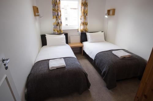 two beds in a small room with a window at Douglas Apartment in Alexandria