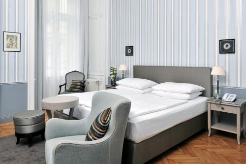 a hotel room with a large bed and a chair at Hotel Kärntnerhof in Vienna