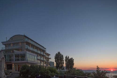 a large building with a sunset in the background at Hotel Sans Souci in Gabicce Mare