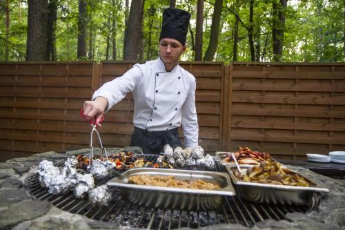 a man in a chefs hat cooking food on a grill at Hotel Zacisze in Turawa