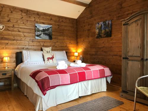 a bedroom with a bed with a red and white blanket at Hill cottage cabins in Fort Augustus