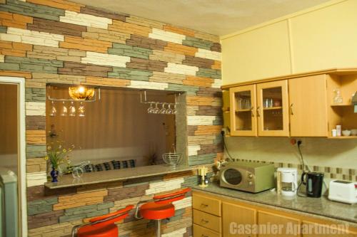 a kitchen with a stone wall with a counter and chairs at Casanier Apartment in Pereybere