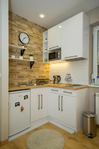 a kitchen with white cabinets and a clock on the wall at Belgrade CITY CENTER Apartments in Belgrade