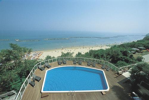 a swimming pool with chairs and a beach at Hotel Sans Souci in Gabicce Mare