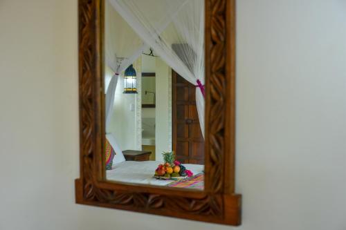 a mirror with a bowl of fruit in a room at Kena Beach Hotel in Matemwe