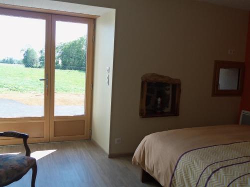 Schlafzimmer mit einem Bett und einer Glasschiebetür in der Unterkunft Gîte de Bel Air in Anglards-de-Salers