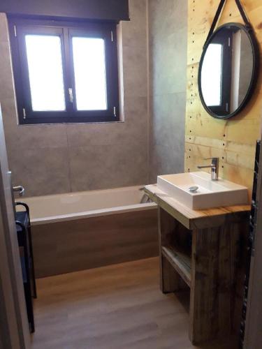 une salle de bain avec un lavabo, une baignoire et un miroir dans l'établissement Chalet du Toit Vosgien, à Gérardmer