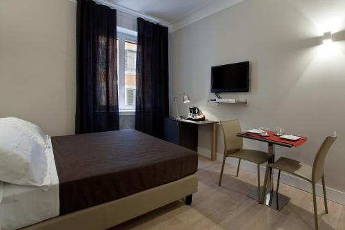 a bedroom with a bed and a desk and a television at Regola Suite in Rome