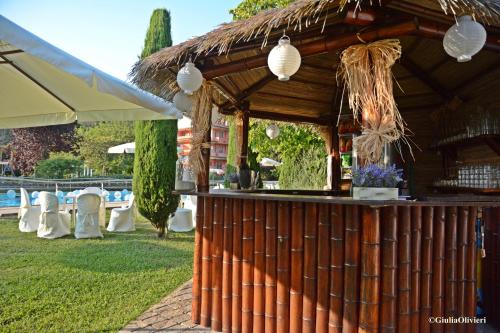a bar with a straw roof in a garden at Hotel Le Rotonde in Massaciuccoli