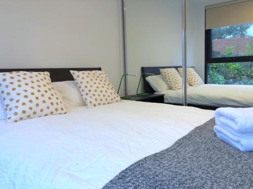 Un dormitorio con una cama blanca con almohadas y una ventana en Pride Bentleigh Apartment with Private Garden, en Melbourne