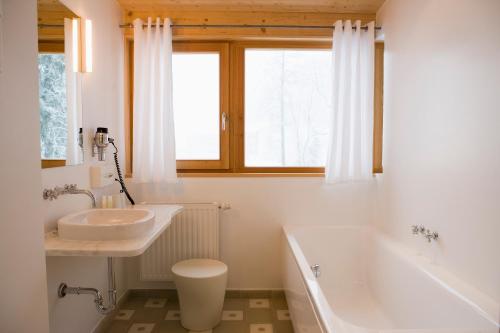 biała łazienka z wanną i umywalką w obiekcie Alpine Spa Hotel Haus Hirt w mieście Bad Gastein