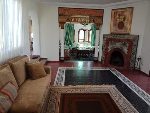 a living room with a couch and a fireplace at Villa meublée face à la mer, Golf et Verdure in El Jadida
