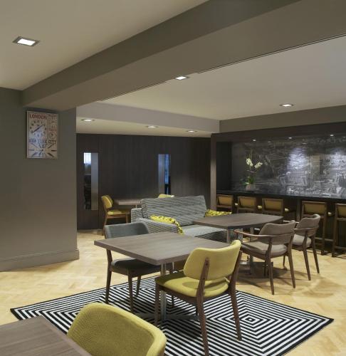a restaurant with tables and chairs and a couch at Citadines Trafalgar Square London in London