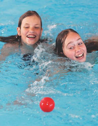two girls in a swimming pool with a ball at Skærbæk Holiday Center in Skærbæk
