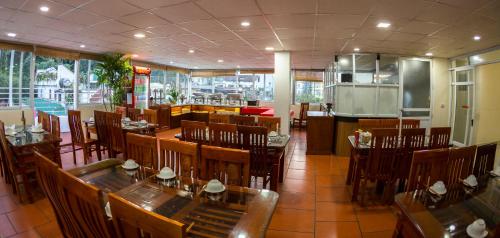 Un restaurante con mesas y sillas de madera y una cocina. en Sapa Land Hotel, en Sa Pa