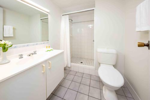 a bathroom with a toilet and a sink and a shower at Hides Hotel in Cairns
