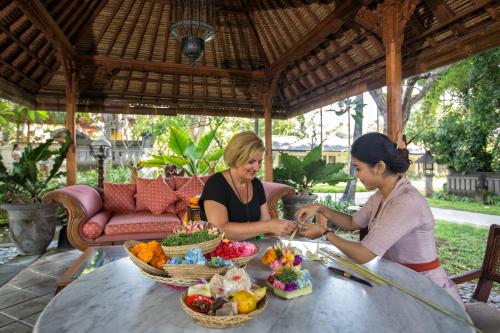 two women sitting at a table with food on it at Segara Village Hotel in Sanur