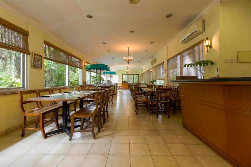 雅加達的住宿－RedDoorz Plus near GBK Senayan，餐厅设有木桌、椅子和窗户。